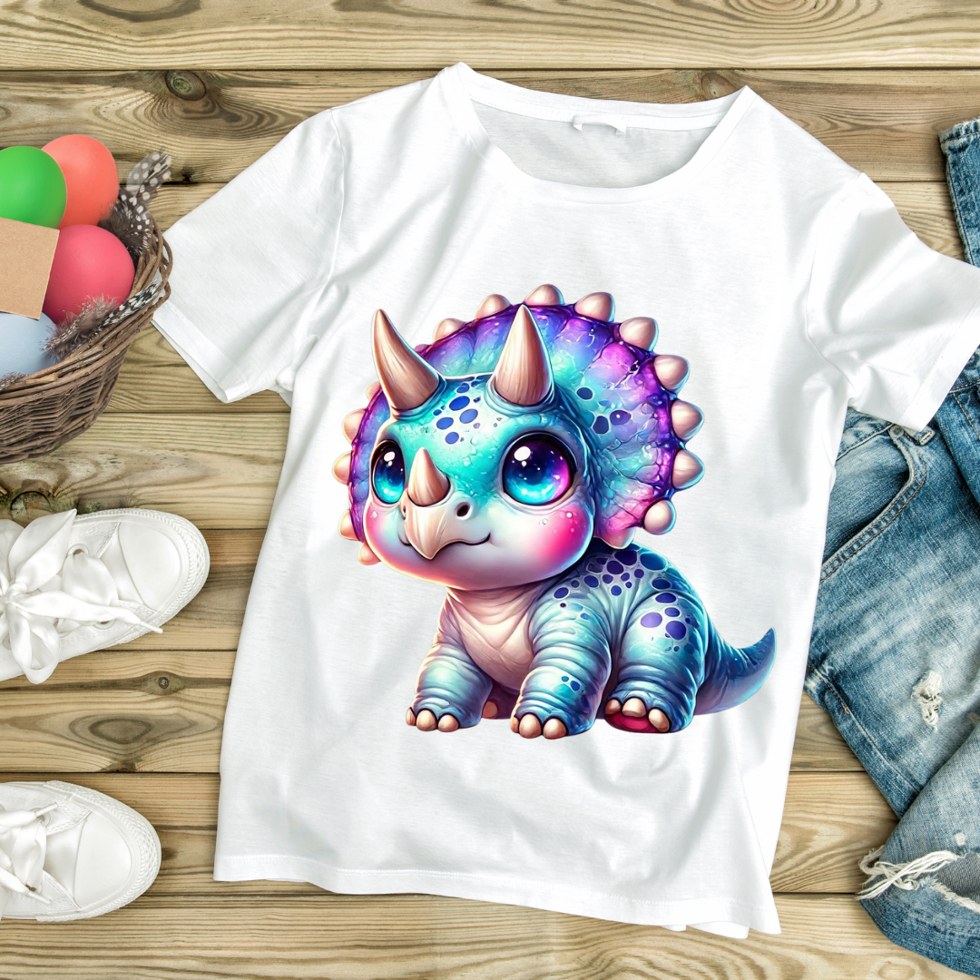 White t-shirt with colorful baby dino graphic featuring a cute triceratops with big eyes
