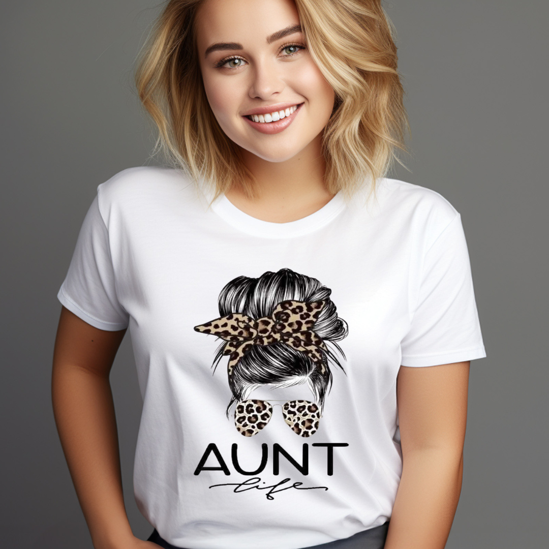 Woman wearing a white messy bun aunt life shirt with leopard print bow and sunglasses design