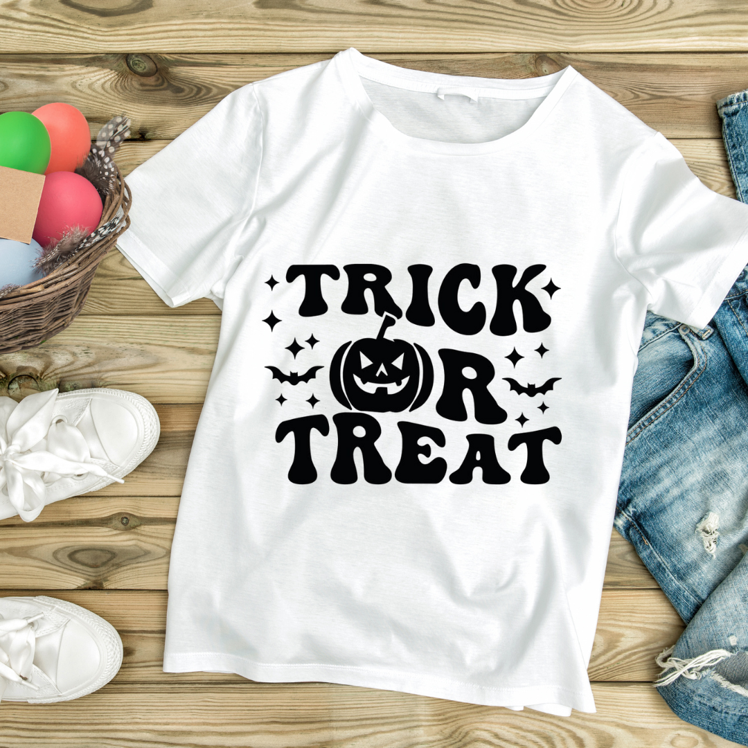 White t-shirt with black trick or treat shirt design featuring a pumpkin and bats on wooden background