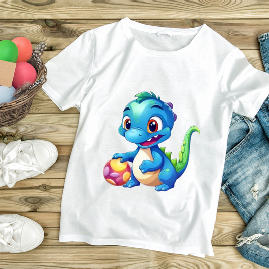 White baby blue dinosaur t-shirt with cute cartoon dinosaur holding a colorful ball on wooden background