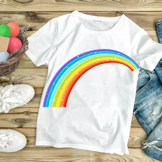White colorful rainbow t-shirt with a bright multi-color arc design laid on wooden surface with casual shoes and denim shorts
