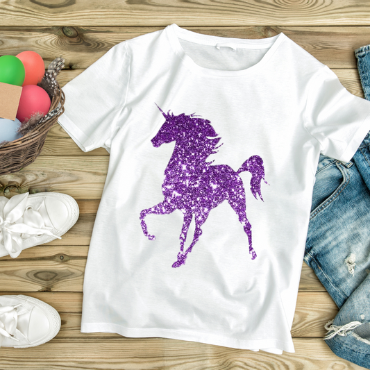 White glitter unicorn t-shirt with purple sparkling unicorn design laid on wooden floor with jeans and white sneakers