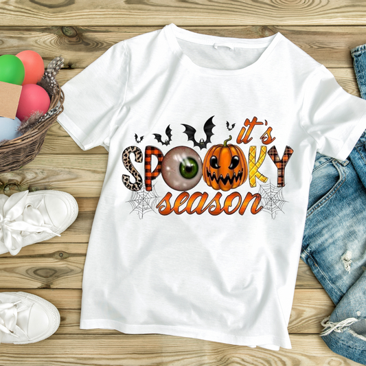 Halloween graphic tee with spooky season design featuring pumpkin, eyeball, bats, and spider webs