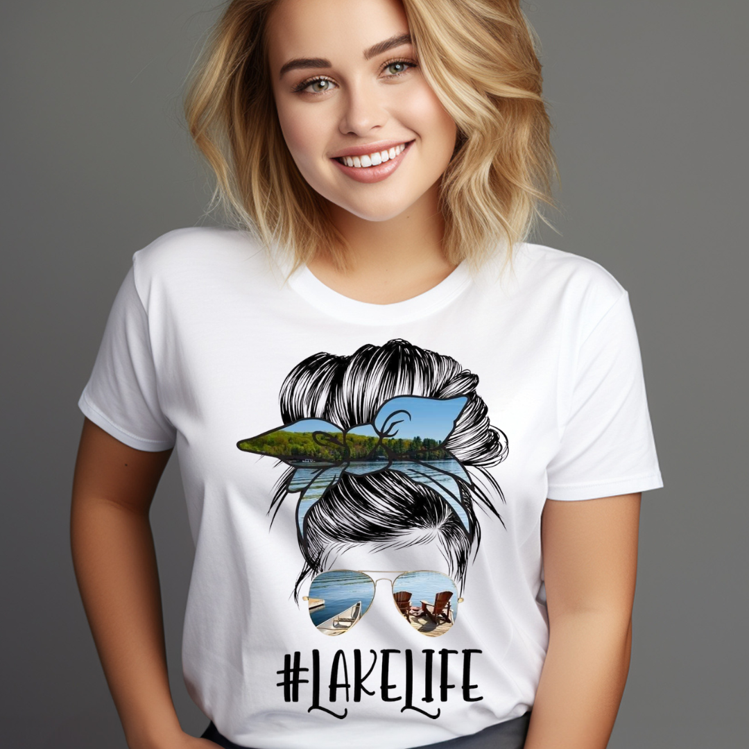 Woman wearing a white Messy Bun Lake Life T-shirt with a lake and chairs design in the hair and sunglasses