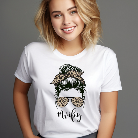 Woman wearing a white Messy Bun Wifey T-Shirt with leopard print hairband and sunglasses design