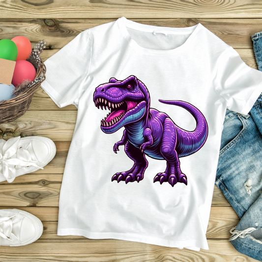 White customizable creations purple T-Rex shirt with vibrant dinosaur graphic laid on wooden floor with sneakers and denim shorts