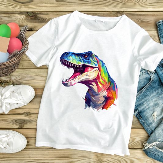 White t-rex graphic tee with colorful artistic dinosaur design laid flat on wooden surface